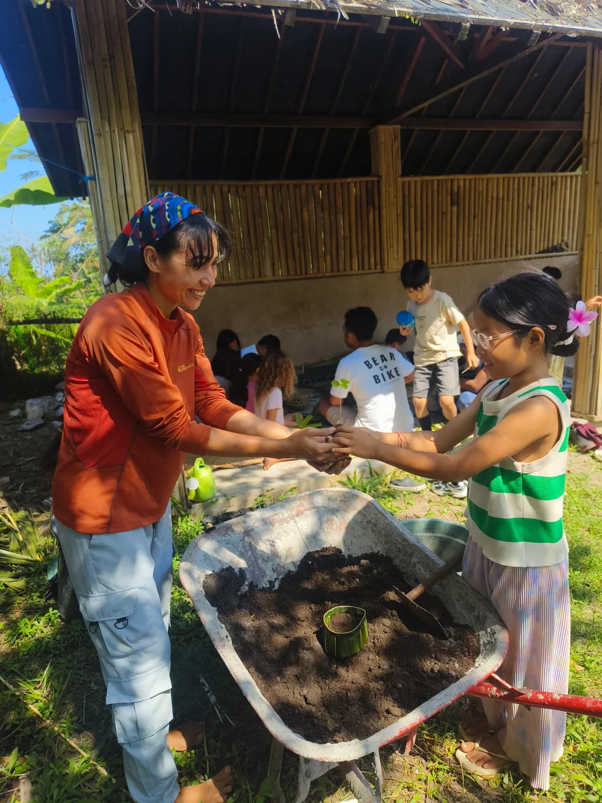 A child planting herbs with a teacher at Empathy School Bali