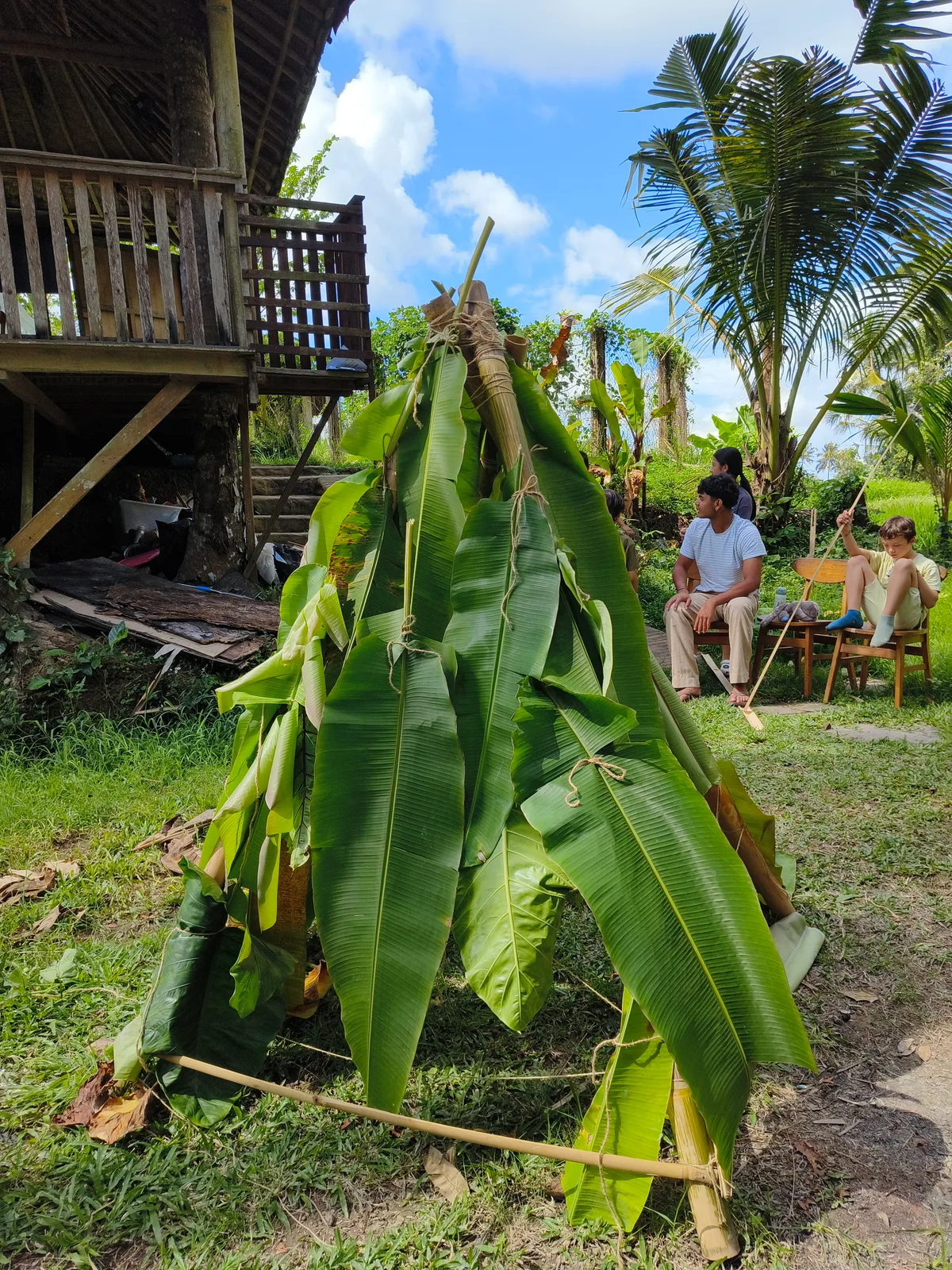 A bamboo frame covered with banana leaves beside a school building at Empathy School Bali