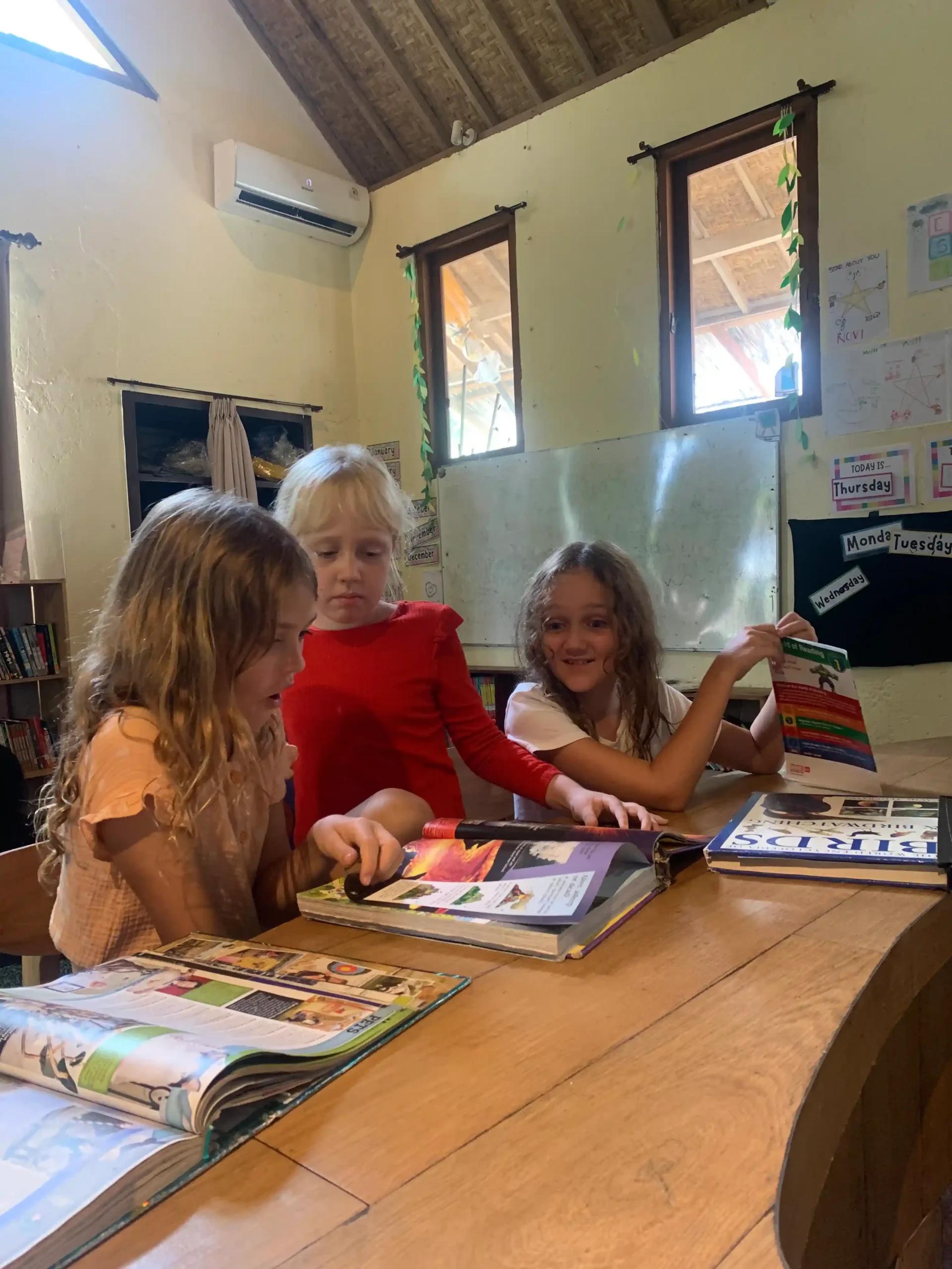 Children sharing books around a classroom table.